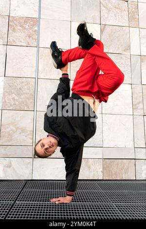 Un jeune homme en pantalon rouge breakdancing exécutant une poignée sur une grille métallique . Concept d'athlétisme et de compétence, comme l'homme est capable d'équilibrer dans un U. Banque D'Images