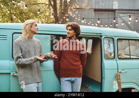 Deux jeunes et belles personnes s'engagent dans une conversation animée à côté d'une charmante camionnette vintage. Banque D'Images