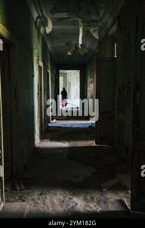 Sombre, couloir en décomposition dans le bâtiment abandonné et silhouette de la personne, image verticale Banque D'Images