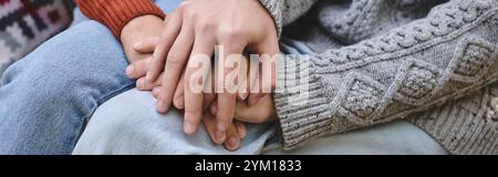 Deux jeunes et belles personnes sont assis étroitement ensemble, leurs mains entrelacées dans une manifestation chaleureuse d'affection. Entourés d'une atmosphère chaleureuse, ils apprécient e. Banque D'Images