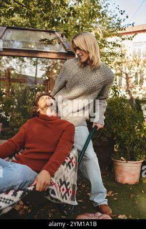 Deux jeunes et beaux hommes partagent un moment de légèreté dans un jardin luxuriant. Vêtus de chandails élégants, ils incarnent la joie comme ils se prélassent dans la chaleur de th Banque D'Images