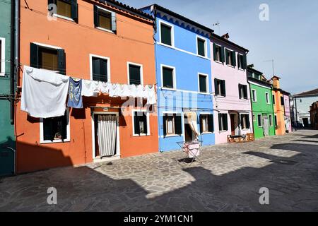 Burano, Italie - 17 avril 2024 : vue sur les maisons colorées de l'île dans la lagune de Venise, linge fraîchement lavé suspendu pour sécher Banque D'Images