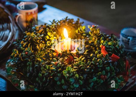 Belles guirlandes ou couronnes de Noël affichées sur la table avec une bougie allumée Banque D'Images