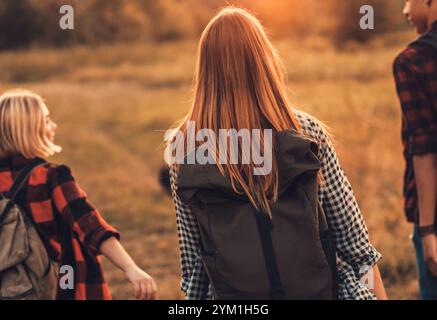 Groupe de quatre amis randonnant à travers la campagne ensemble au coucher du soleil. Banque D'Images