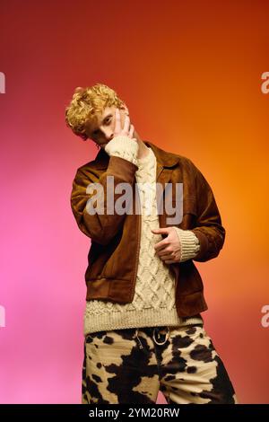 Un jeune homme confiant met en valeur la mode festive des fêtes dans un pull confortable et une veste élégante sur un fond vibrant. Banque D'Images