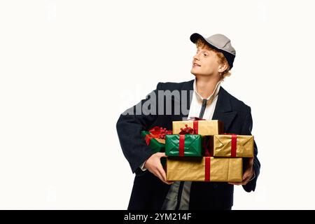 Un homme élégant se tient confiant, tenant plusieurs cadeaux magnifiquement enveloppés ornés de rubans. Habillé dans une tenue de vacances moderne. Banque D'Images