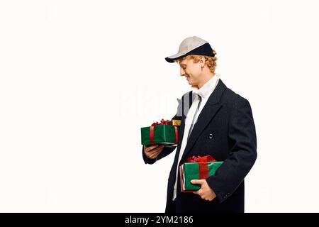 Habillé pour l'esprit des fêtes, un homme présente une mode unique avec des cadeaux de Noël à la main. Banque D'Images