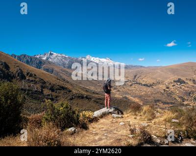 Parc national de Huascaran, Ancash, Pérou - 24 juillet 2024 : jeune homme blanc se tient sur un rocher admirant les montagnes sur son chemin vers la lagune de Churup à Ancas Banque D'Images