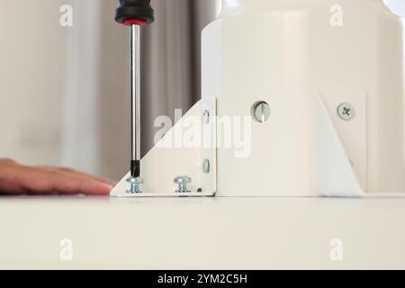 Homme asiatique assemblant des meubles de table blancs à la maison Banque D'Images