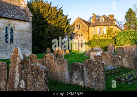 Lumière du soir sur le vieux presbytère vu depuis le cimetière de l'église Saint-Jean-Baptiste dans le village Cotswold de Great Rissington, Gloucestershire Banque D'Images