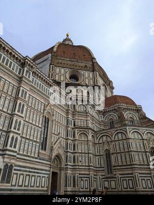 Cathédrale de Florence avec sa façade en marbre complexe et son emblématique dôme rouge sous un ciel nuageux. Florence, Italie, Europe Banque D'Images