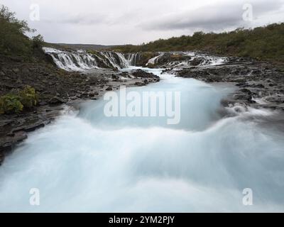 Cascade sereine avec de l'eau bleue brumeuse cascades sur les rochers dans un cadre tranquille. Islande Banque D'Images