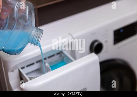Versez le détergent à lessive de la bouteille bleue dans la machine à laver pour des résultats optimaux Banque D'Images