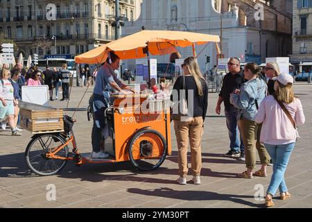 Marseille. France - 20 novembre 2024 : un vendeur de nourriture de rue local grillant du poisson sur un tricycle dans le vieux port de Marseille. La scène capture un mars animé Banque D'Images