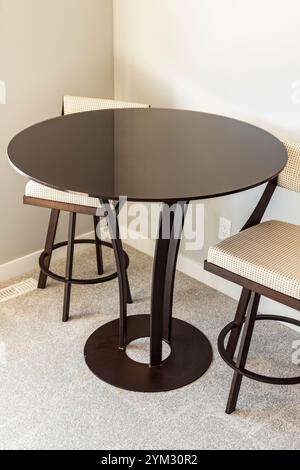 Une table ronde avec deux chaises est installée devant un mur. La table est en verre et a un design unique. Les chaises sont en bois et ont un arbre- Banque D'Images