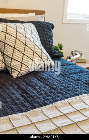 Un lit avec une couette bleue et un oreiller blanc. Le lit est fait et les oreillers sont soigneusement disposés Banque D'Images