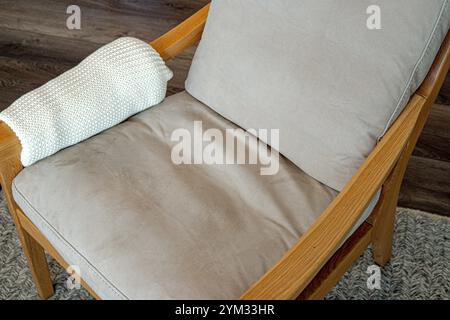 Une chaise en bois avec une couverture blanche drapée sur le bras. La chaise est vide et la couverture est soigneusement pliée Banque D'Images