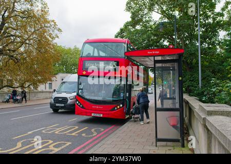 Une jeune mère avec son enfant dans une poussette embarquant dans un bus rouge de Londres sur Kew Bridge Greater West London England UK Banque D'Images