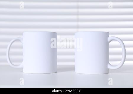 Mugs en céramique vierges sur table blanche. Maquette pour le design Banque D'Images