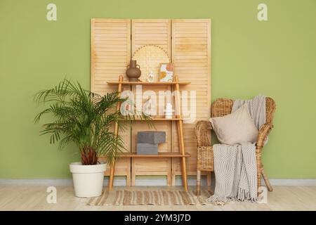 Intérieur d'un salon élégant avec fauteuil en osier, couverture confortable, table console et écran pliant Banque D'Images