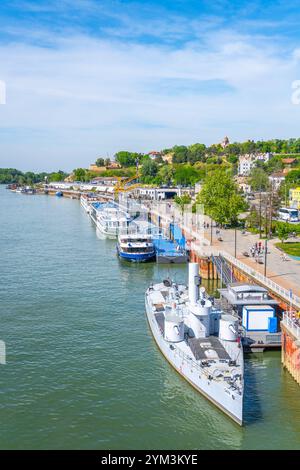 Le moniteur yougoslave Sava est amarré le long de la rive à Belgrade, en Serbie, entouré de bateaux et d'une promenade dynamique au bord de l'eau, offrant des vues sereines sur la rivière par temps clair. Banque D'Images