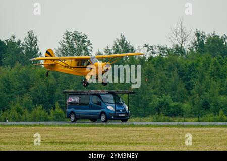 Liepaja, Lettonie- 16 juin 2024 : Stunt risqué et dangereux, un petit avion tente d'atterrir sur le toit d'un minibus, pilote de cascadeur atterrit un avion sur un minibus Banque D'Images