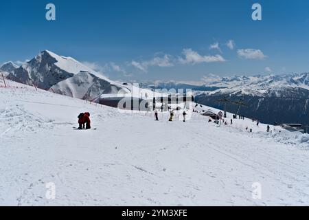 Paysage de montagne enneigé avec des skieurs profitant d'une journée ensoleillée dans les montagnes - Rosa Peak, Russie 15 avril 2024 Banque D'Images