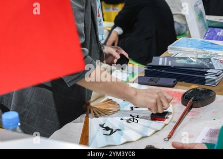 Bakou, Azerbaïdjan, Azerbaïdjan. 20 novembre 2024. Un homme tamponne un éventail de papier avec de la calligraphie chinoise dessus au pavillon chinois à la COP29. (Crédit image : © Bianca Otero/ZUMA Press Wire) USAGE ÉDITORIAL SEULEMENT! Non destiné à UN USAGE commercial ! Banque D'Images