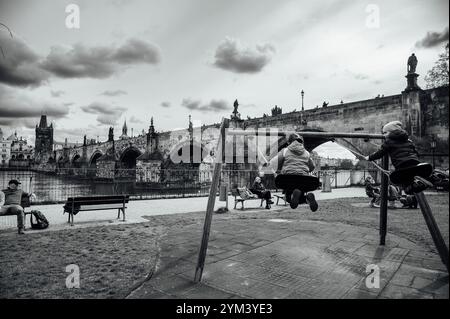 PRAGUE, TCHÉQUIE - 25 MARS 2023 : Pont Charles et enfants se balançant au premier plan. Banque D'Images