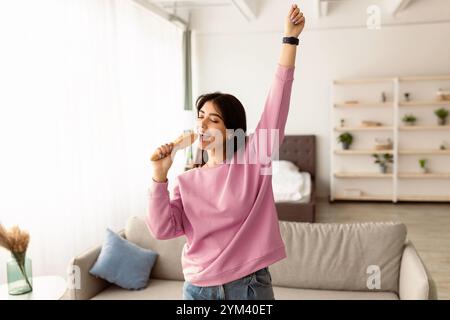 Jeune femme dansant et chantant en brosse à cheveux Banque D'Images