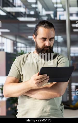 Programmeur faisant du débogage logiciel en utilisant la tablette, vérifiant les erreurs dans les lignes de code. Homme travaillant au bureau, corrigeant les erreurs de codage à l'aide d'un appareil, recherchant les vulnérabilités de sécurité de l'entreprise Banque D'Images