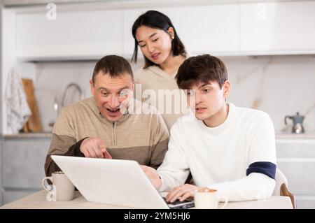 Une famille amicale regarde quelque chose ensemble sur Internet ou des chats vidéo via un ordinateur portable Banque D'Images