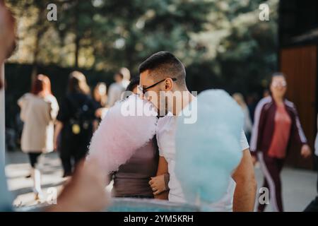 Jeune homme appréciant la barbe à papa à une foire en plein air Banque D'Images