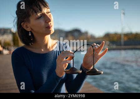 personne tenant l'instrument de cloche tibetian tingsha pour la thérapie de vibration et de guérison sonore, le corps de cymball ting-sha et la technique de récupération de l'esprit, femme Banque D'Images