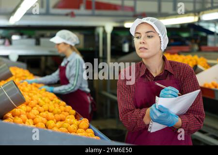 Jeune femme responsable de l'inspection du flux de travail de l'atelier de tri des agrumes Banque D'Images