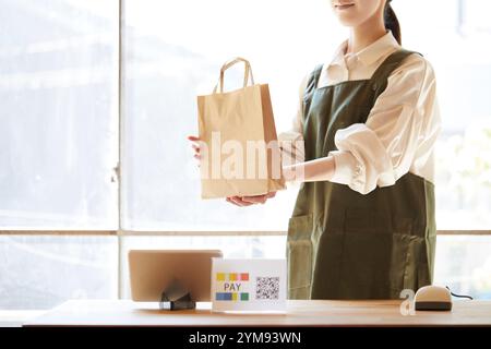 Femme commerçant à la caisse avec paiement sans espèces Banque D'Images