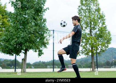 Jeune homme jouant au football dans le parc Banque D'Images