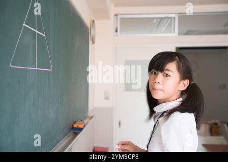 Écoles primaires fille debout devant le tableau noir Banque D'Images