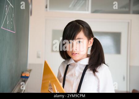 Écoles primaires fille debout devant le tableau noir Banque D'Images