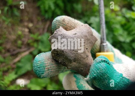 Fragment d'un produit en argile ressemblant à une figurine humaine, ancien artefact archéologique en main, Russie Banque D'Images
