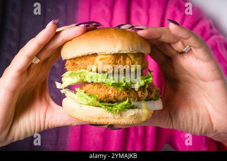 Femme tenant un hamburger de poisson ou de poulet avec les deux mains Banque D'Images