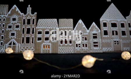 Panorama de vieilles maisons. Fabriqué à la main. Les maisons sont découpées dans du carton. Peint en blanc. Fond noir. Il y a de la lumière dans les fenêtres. Devant les maisons se trouve une guirlande qui brille au chaud. Idée pour le décor. Banque D'Images