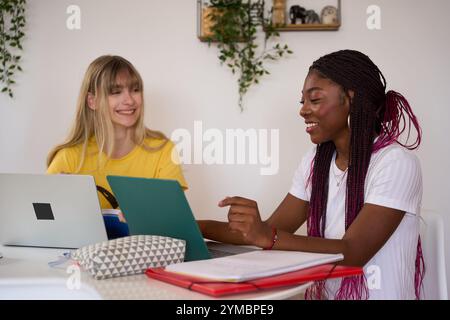 Étudiants multiethniques collaborant sur un projet à l'aide d'ordinateurs portables et de tablettes Banque D'Images