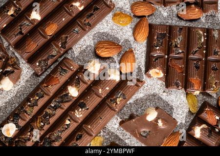 Morceaux de chocolat cassés avec des noix et des raisins secs sur une vue de dessus de fond en pierre Banque D'Images