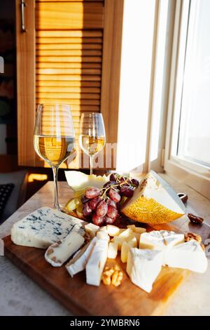 Melon juteux, raisins parfumés, fromage en tranches et noix. Deux verres de champagne. De délicieuses collations sur un plateau en bois sur la table. Une pause romantique légère Banque D'Images