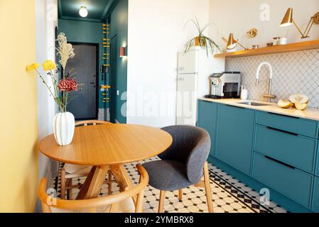 Une élégante table ronde en bois avec un vase et des chaises en matériaux naturels. Cuisine moderne avec des éléments contrastés. Une salle à manger propre confortable avec Banque D'Images