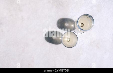 Deux élégants verres à longue tige avec des boissons alcoolisées fraîches sur une table en marbre. Vue de dessus. Champagne en tasses. Vin mousseux parfumé au su brillant Banque D'Images