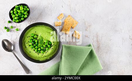 Soupe à la crème de pois verts avec des craquelins sur une table grise. Vue de dessus. Banque D'Images
