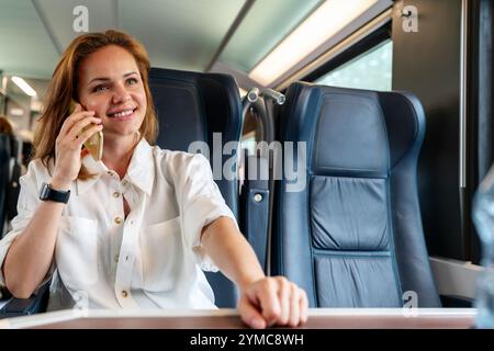 Jeune femme d'affaires parlant sur son smartphone tout en voyageant pour affaires en train. Banque D'Images