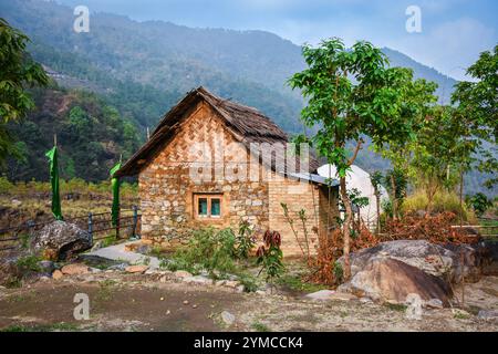 Chalet en pierre avec toit de chaume, crêtes de montagne de l'Himalaya Banque D'Images